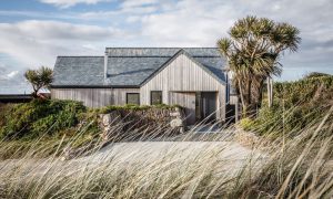 Contemporary coastal house with timber cladding and stone wall featured in Architecture Vogue Magazine