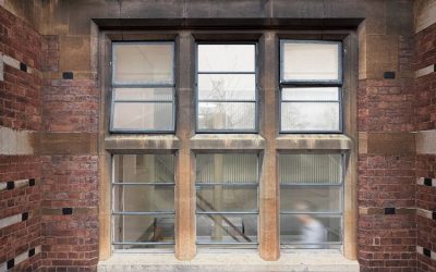 Historic brick courtyard facade with stone-framed industrial windows, showcasing restored heritage architecture and natural light in a contemporary architectural renovation.