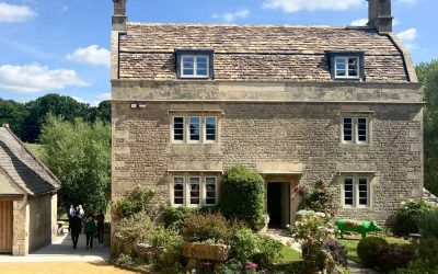 Traditional English countryside stone house with slate roof, symmetrical windows, and landscaped cottage garden – classic heritage architecture featured in an architecture magazine
