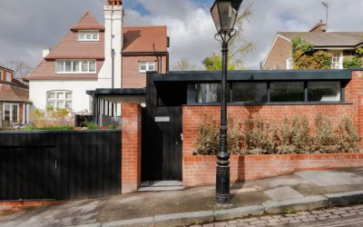 Modern brick entrance and gate contrasting with traditional home featured in Architecture Magazine.